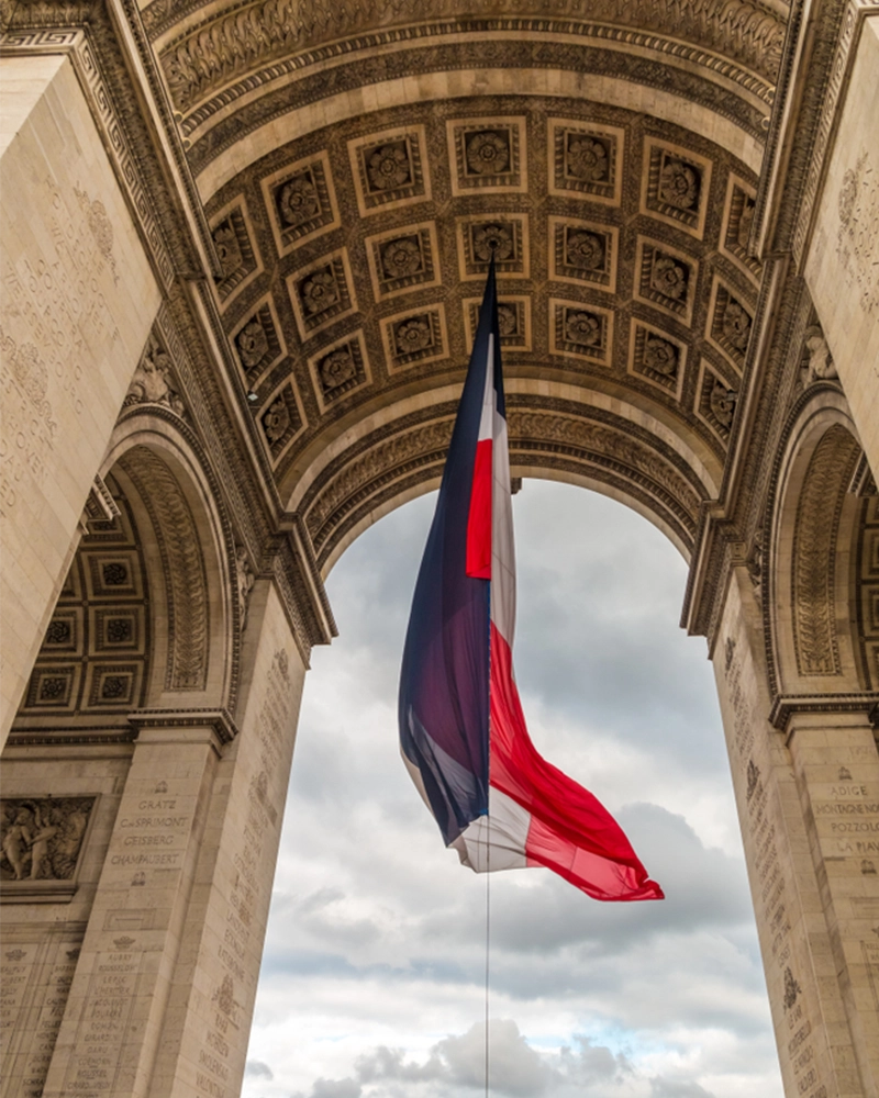 Close-up view under the Arc de Triomphe de l'Étoile in Paris with a large French flag during the ceremony to recall the sacrifice of an unknown French soldier who gave his life during World War I.